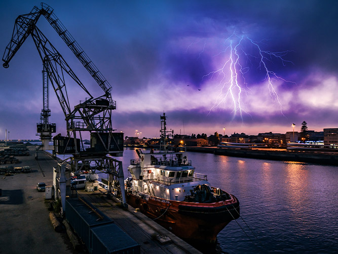 Night view of a shipping port with lightning and thunderstorm nearby 一个运输口岸的夜视图有闪电和雷暴附近的